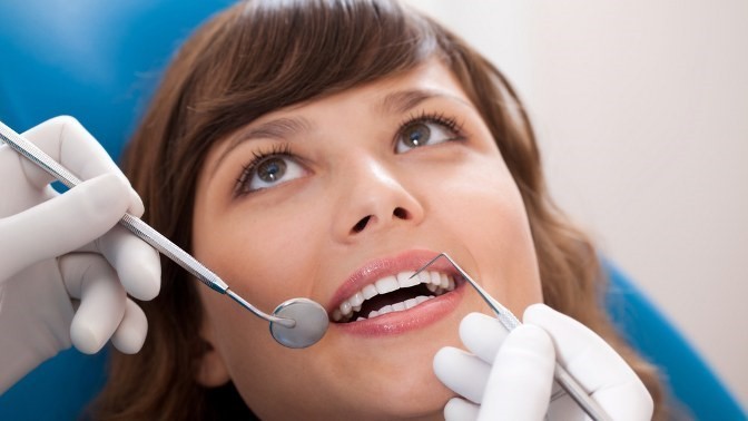 Стоматолог смотрит зуб